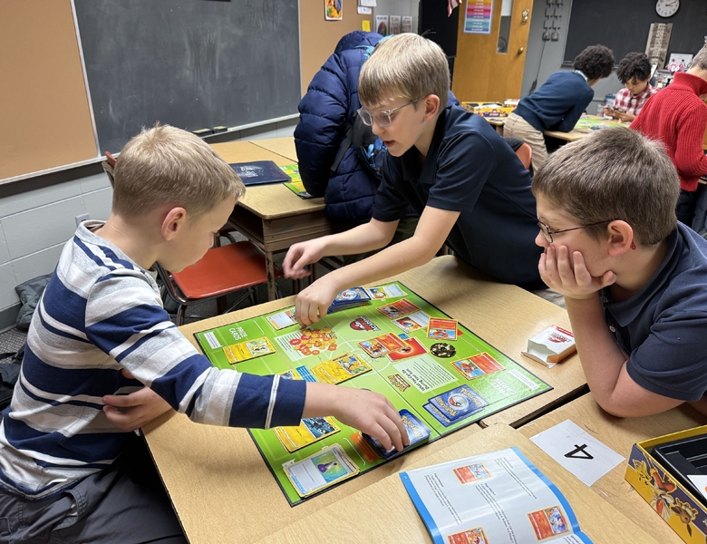 Three students playing the Pok&eacute;mon Trading Card Game during Pok&eacute;mon Club at OLPI.