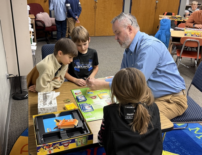 Teacher helping students learn the Pok&eacute;mon Trading Card Game during Pok&eacute;mon Club at OLPI.